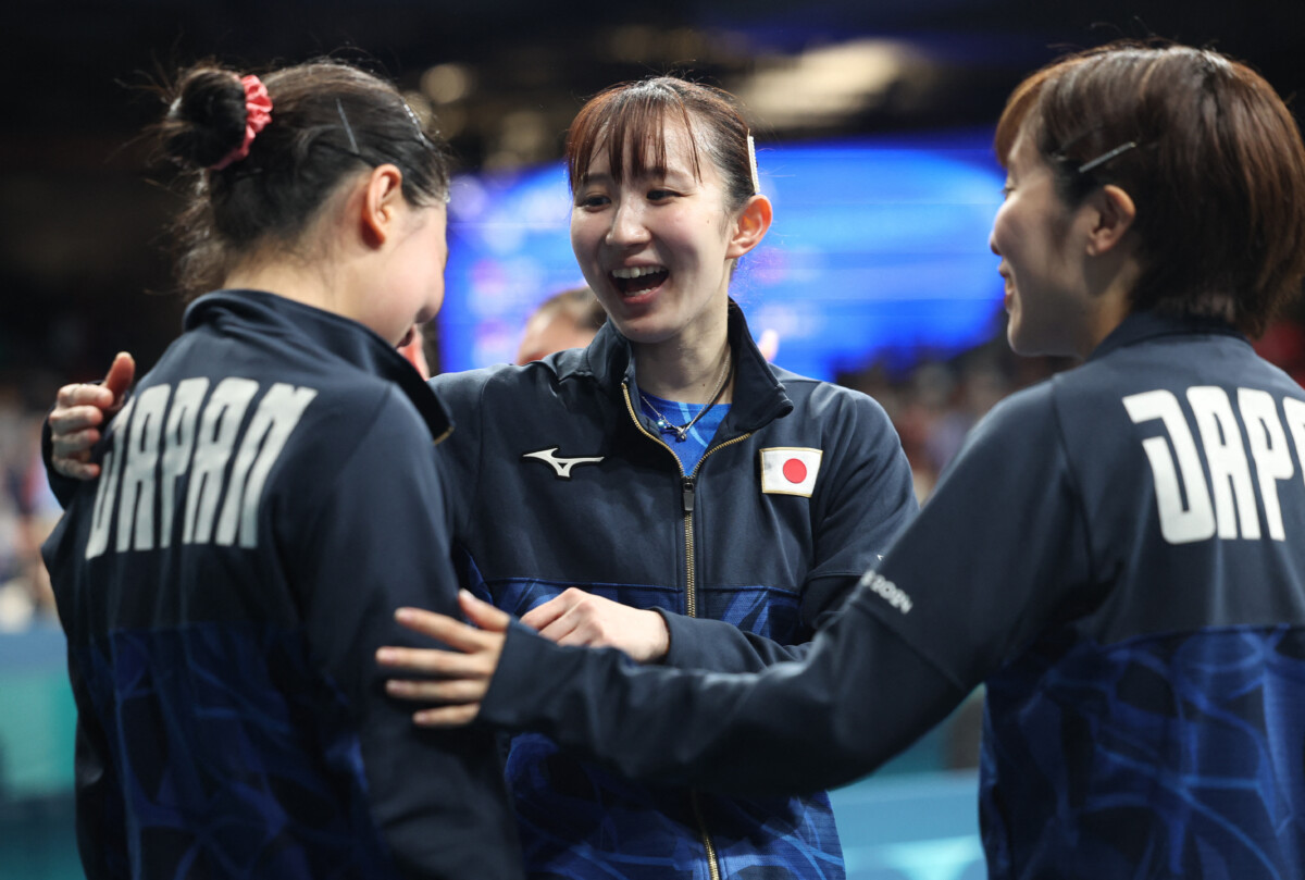 卓球女子団体で日本はドイツを破って決勝進出を決めた。チーム最年少の張本美和（左）を早田ひな（中）と 平野美宇が激励する（写真・ロイター/アフロ）