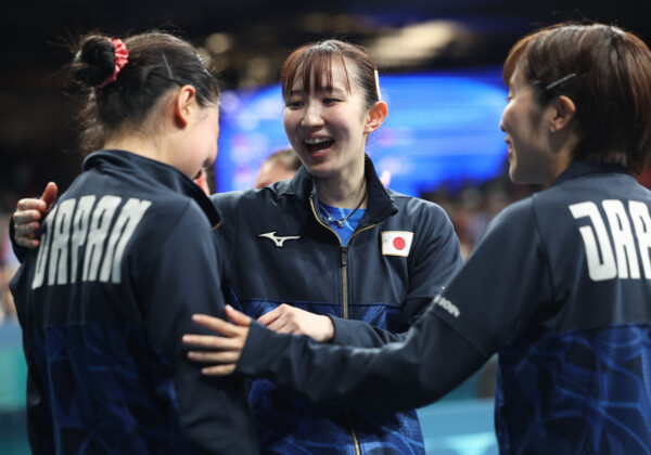 卓球女子団体で日本はドイツを破って決勝進出を決めた。チーム最年少の張本美和（左）を早田ひな（中）と 平野美宇が激励する（写真・ロイター/アフロ）